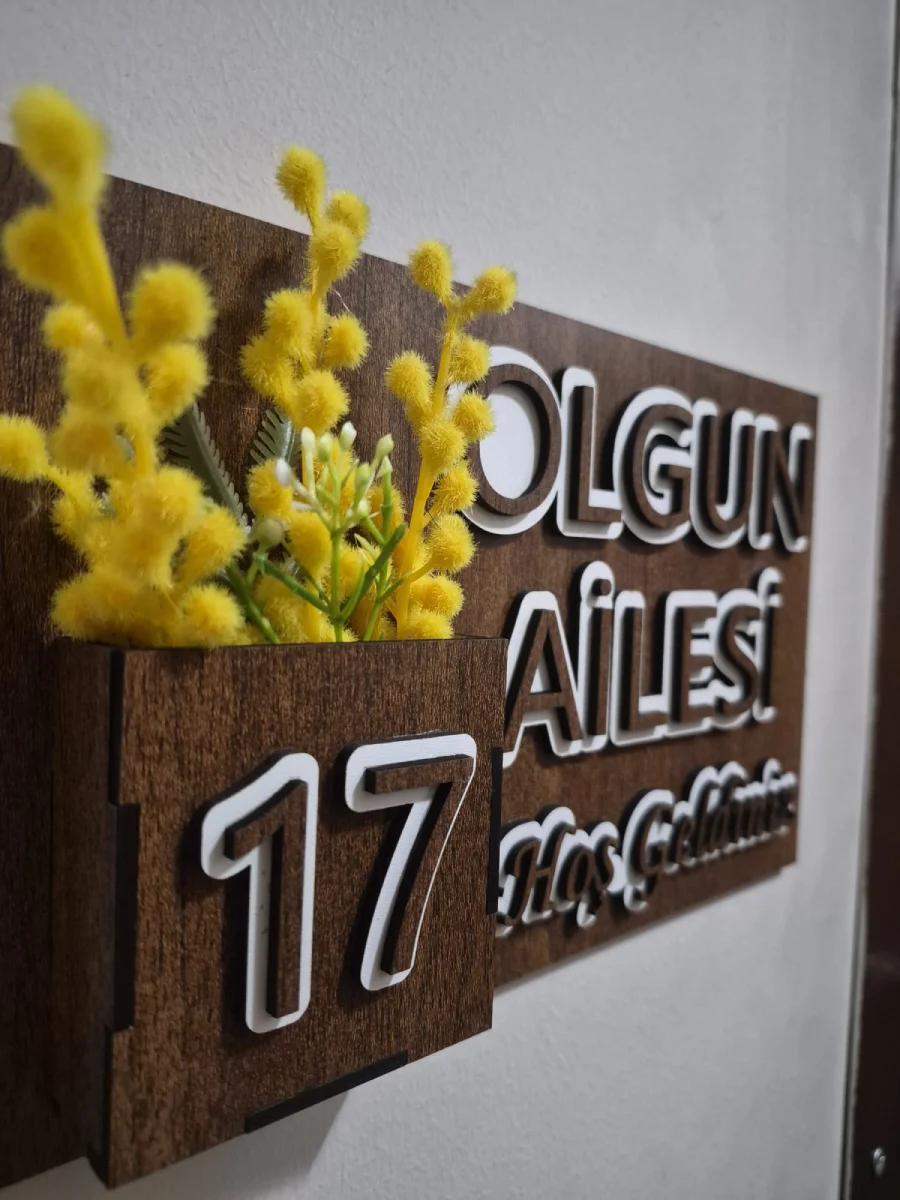 Kabartmalı aile adı ve çiçeklik detaylı MDF kapı isimliğinin açılı görünümü